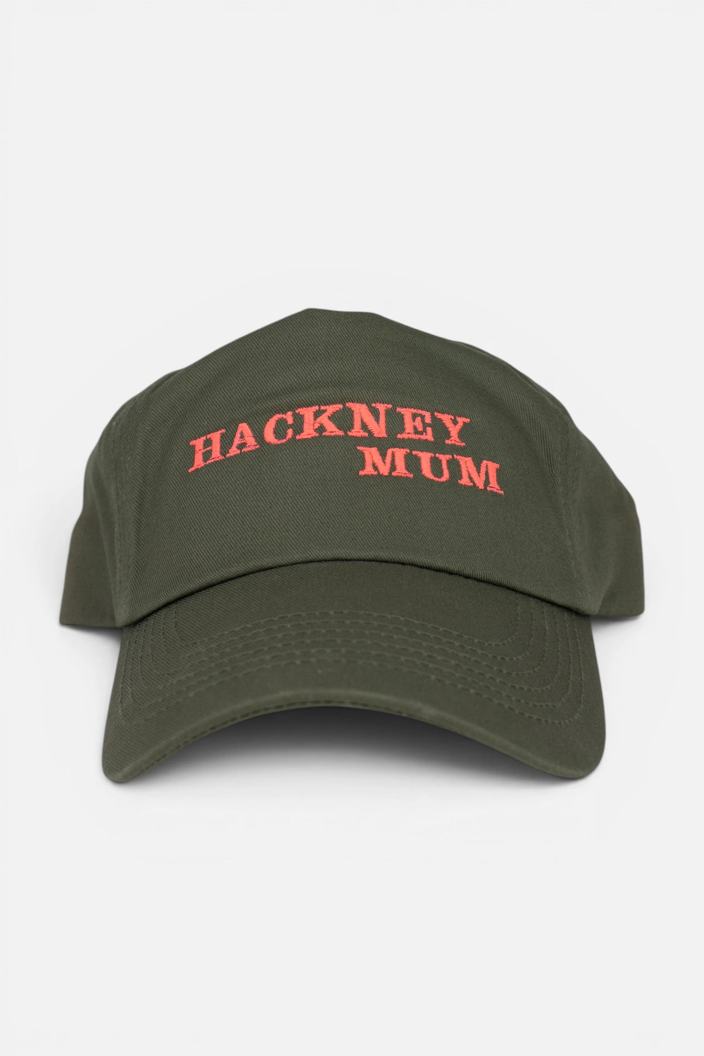 An olive green baseball cap with 'HACKNEY MUM' embroidered in fluorescent coral orange across the front, shown against a plain light gray background.