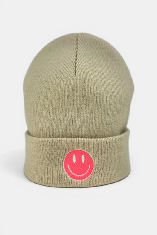 A beige beanie hat featuring a folded cuff with a fluorescent coral orange embroidered smiley face logo, set against a plain light gray background.