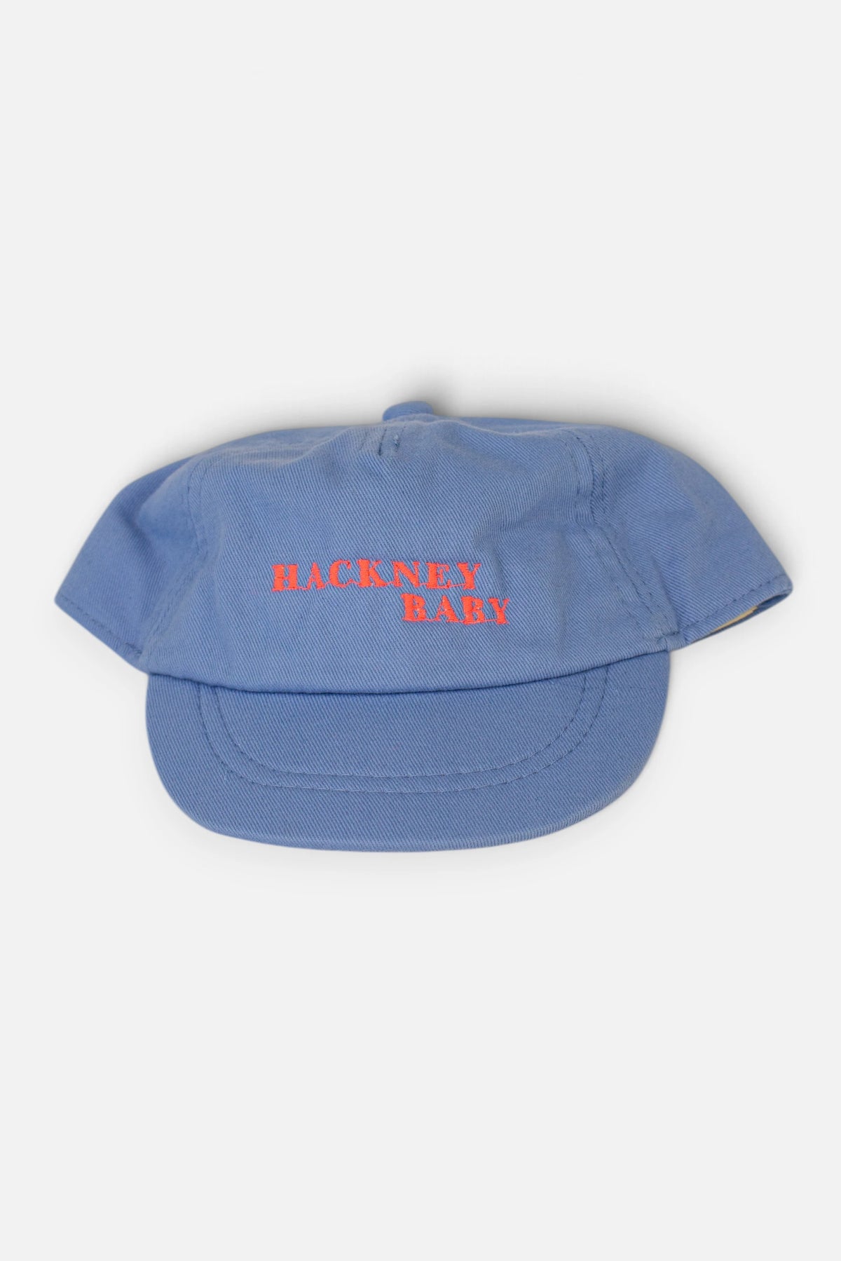 A light blue baseball cap with 'HACKNEY BABY' embroidered in fluorescent coral orange across the front, shown against a plain light grey background.