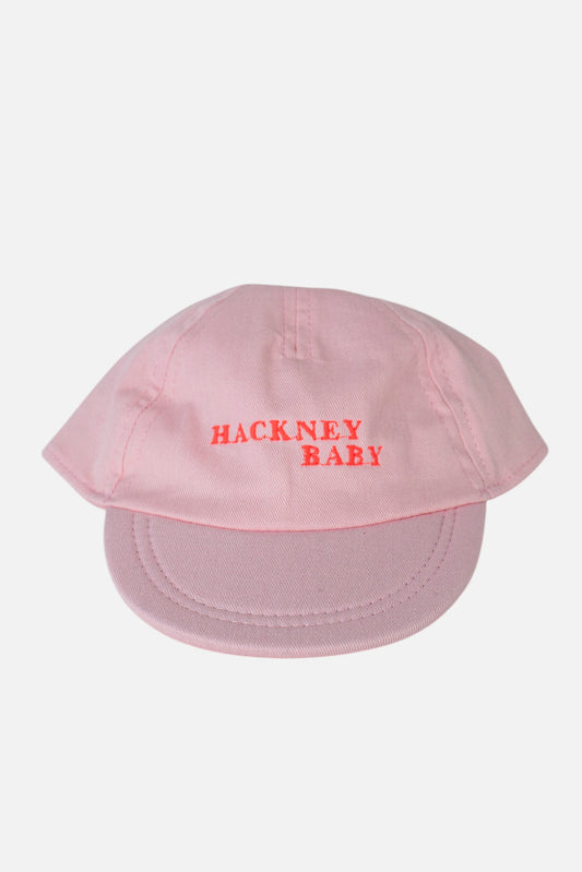 A light pink baseball cap with 'HACKNEY BABY' embroidered in fluorescent coral orange across the front, shown against a plain light grey background.