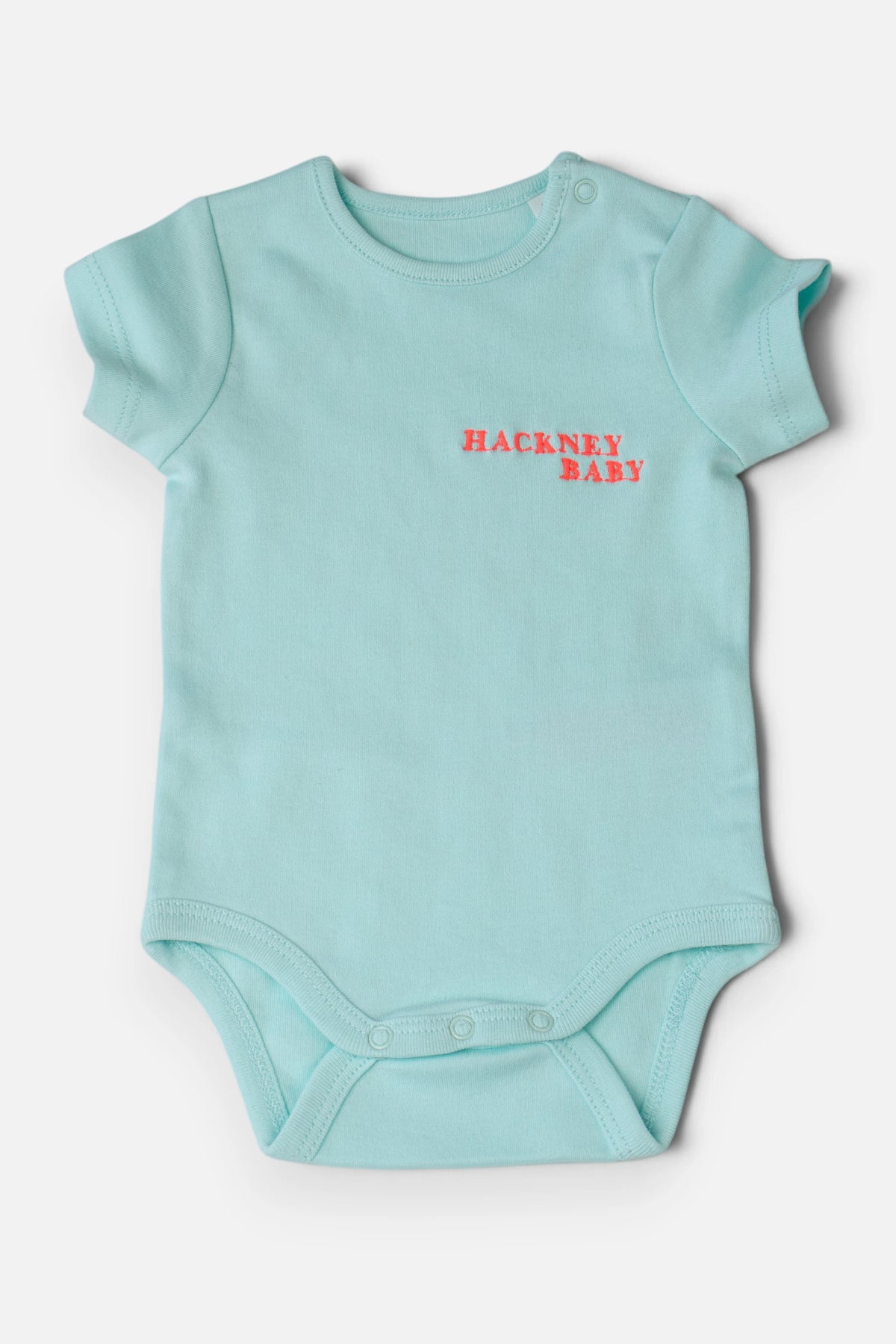 A mint green baby bodysuit with short sleeves and a fluorescent coral orange 'HACKNEY BABY' logo embroidered on the chest, displayed flat against a light grey background.