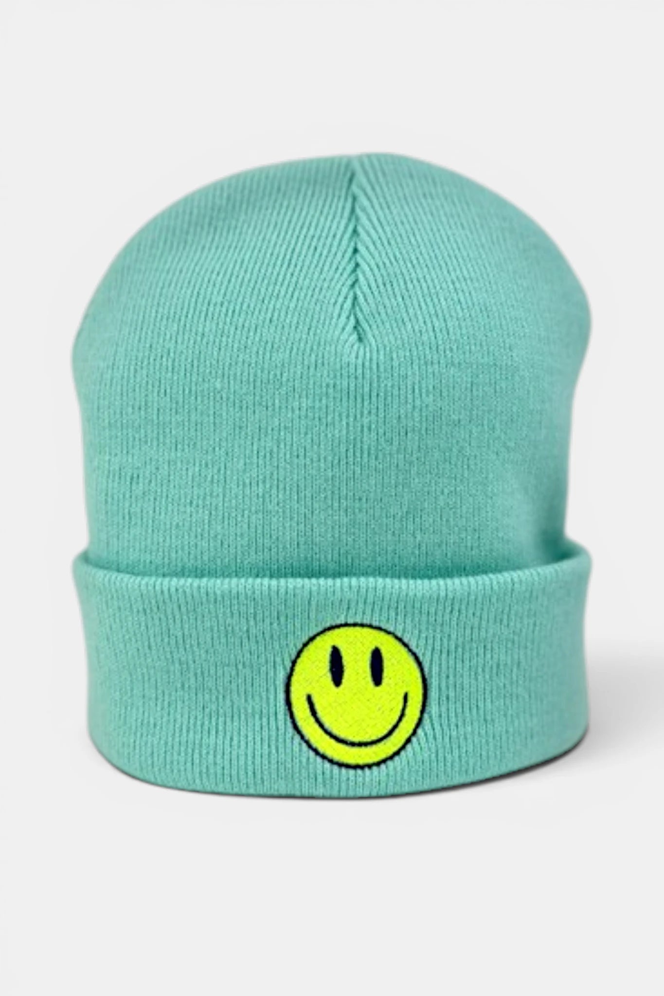 A mint green beanie hat featuring a yellow smiley face patch on the front cuff, set against a plain light gray background.