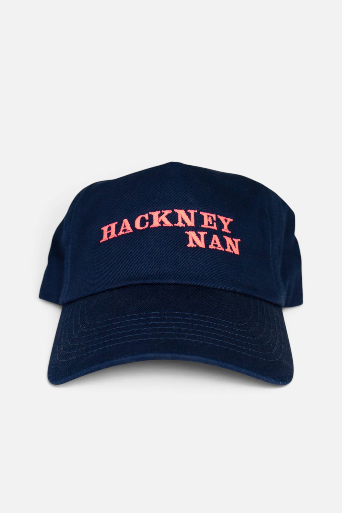 A navy blue baseball cap with 'HACKNEY NAN' embroidered in fluorescent coral orange across the front, shown against a plain light grey background.