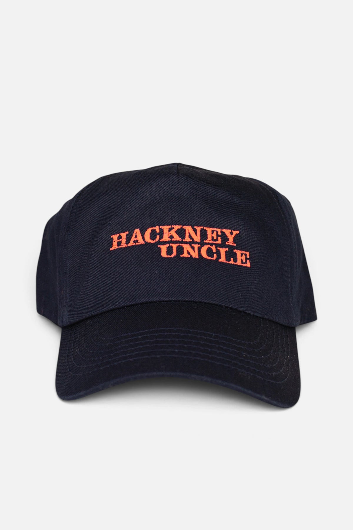 A navy blue baseball cap with 'HACKNEY UNCLE' embroidered in fluorescent coral orange across the front, shown against a light grey background.