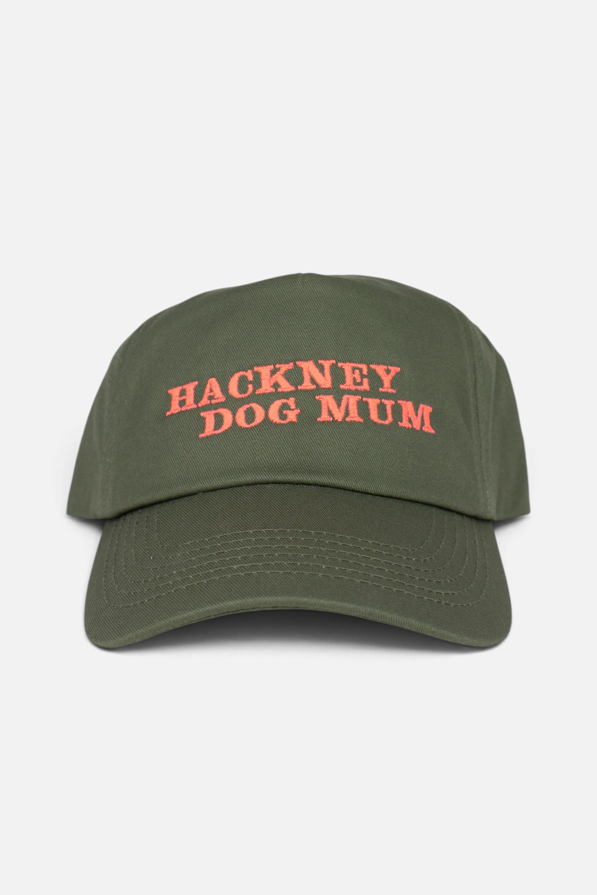 An olive green baseball cap with 'HACKNEY DOG MUM' embroidered in coral-orange text on the front, shown against a plain light grey background.